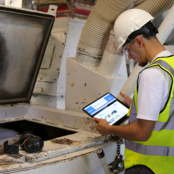 Ein Auszubildender im Betonwerk überprüft etwas. Dabei schaut er auf ein Tablet.
