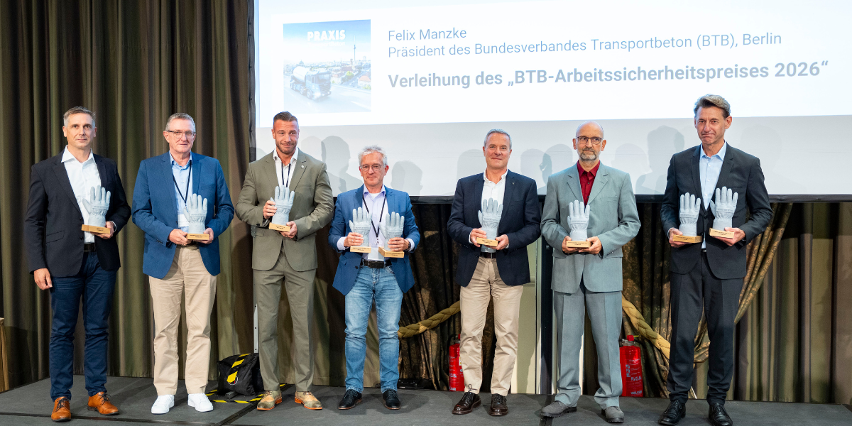 Preisträger stehen mit Siegerpokalen auf einer Bühne