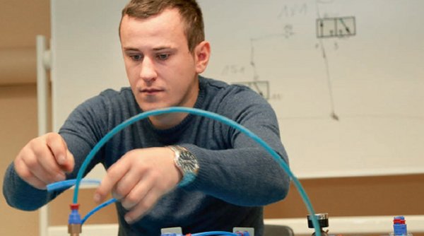 Ein Auszubildender arbeitet in einem Klassenraum an einem Schaltsystem. 