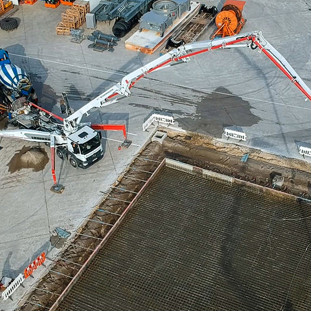 Baustellensituation von oben aufgenommen. Fahrmischer und Betonpumpe bei der Arbeit.