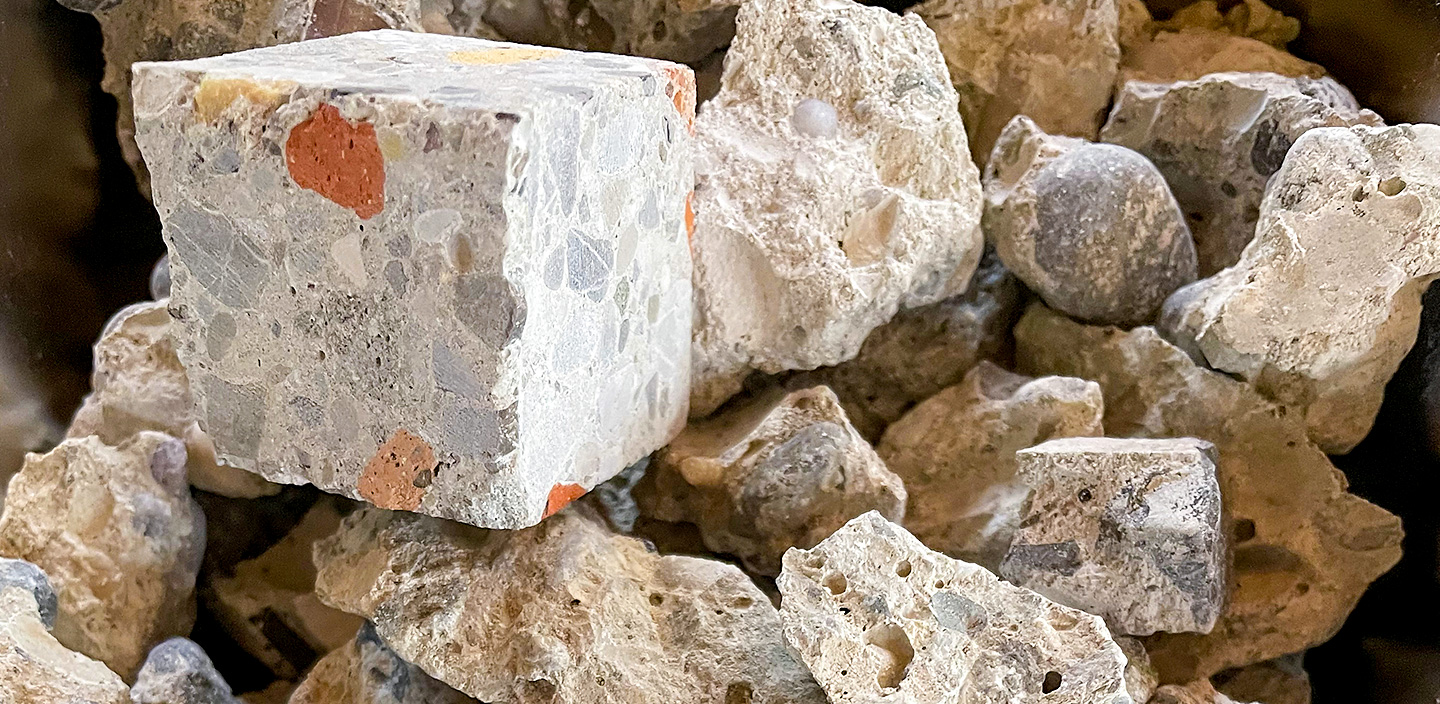 Ansammlung rezyklierter Gesteinskörnung und Probewürfel aus R-Beton